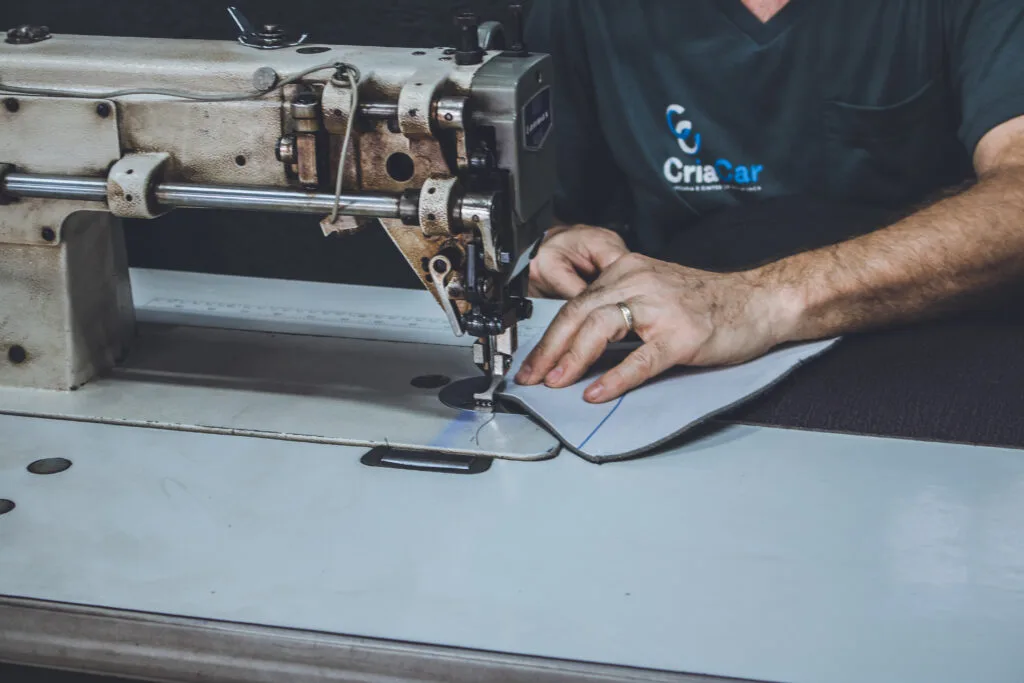 Profissional da CriaCar costurando tecido para tape&ccedil;aria automotiva